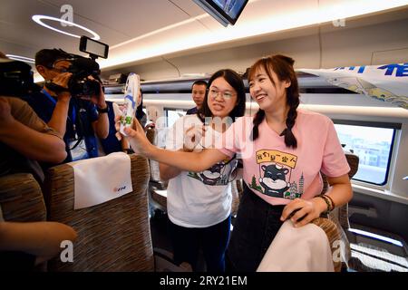 (230928) -- FUZHOU, 28 settembre 2023 (Xinhua) -- due passeggeri provenienti da Taiwan della Cina sudorientale parlano con la loro famiglia in una video chat mentre prendono il treno proiettile Fuxing G9801 sulla ferrovia ad alta velocità Fuzhou-Xiamen-Zhangzhou nella provincia del Fujian della Cina sudorientale, 28 settembre 2023. La ferrovia ad alta velocità più veloce della Cina ha iniziato a funzionare giovedì, con treni che viaggiano a una velocità massima di 350 km/h lungo la costa occidentale dello stretto di Taiwan. Un treno proiettile Fuxing G9801 partì da Fuzhou, la capitale della provincia del Fujian della Cina sud-orientale, alle 9:15 del mattino, segnando l'apertura dei 277 km fu Foto Stock