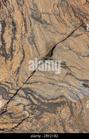 Motivo ondulato grossolano in granito marrone. Motivo di sfondo di pietra naturale. Rottura strutturale diagonale nella superficie. Area grigia e scura isolata Foto Stock