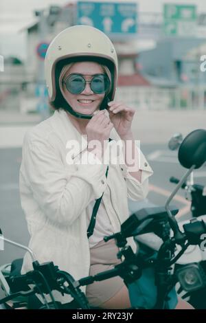 donna che indossa un elmetto di sicurezza in piedi sulla strada cittadina sorride con la felicità del viso Foto Stock