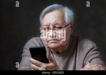 Nonna con gli occhiali che guardano lo smartphone, primo piano Foto Stock