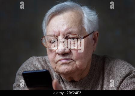 Nonna con gli occhiali che guardano lo smartphone, primo piano Foto Stock