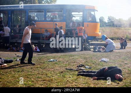 28 settembre 2023, Sassonia, Wiederau: Le persone che rappresentano le vittime di un attacco terroristico si trovano davanti a un tram durante un'esercitazione terroristica. Circa 150 tirocinanti della Croce Rossa tedesca, dei samaritani e del Johanniter della Sassonia e della Sassonia-Anhalt prendono parte a una situazione di terrore messa in scena alla fine di una settimana di addestramento. C'è stato un attacco con numerose vittime: L'autore si è trincerato, sono sparati colpi, c'è fumo, la polizia pesantemente armata e incappucciata attacca l'edificio. Successivamente, i paramedici di emergenza devono curare i feriti. Foto: Jan Woitas/dpa Foto Stock