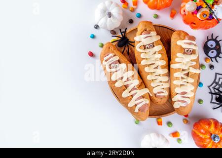 Divertenti hot dog per la festa di Halloween o il brunch per i bambini. Hot dog classici con occhi al formaggio e salsa cheesy mayo, con decorazioni di Halloween, Top vi Foto Stock