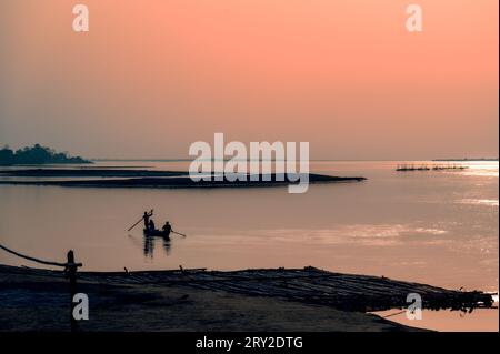 Silhouette di una persona su una barca. Pescatori al tramonto, fiume Brahmaputra. Dibrugarh, Assam, India. Foto Stock