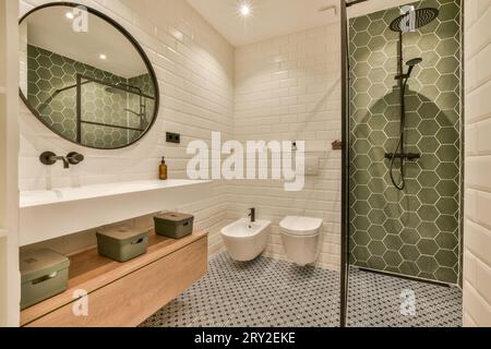 Interni di un elegante bagno illuminato con specchio sul lavandino e cabina doccia con WC in una casa moderna Foto Stock
