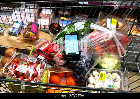 waitrose alimentari in tram con telefono che mostra l'app waitrose in vista, ramsgate town, east kent, uk, settembre 28 2023 Foto Stock