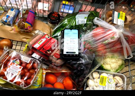 waitrose alimentari in tram con telefono che mostra l'app waitrose in vista, ramsgate town, east kent, uk, settembre 28 2023 Foto Stock