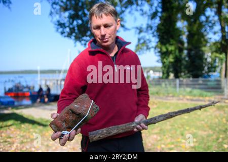 28 settembre 2023, Sassonia-Anhalt, Arendsee: Sven Thomas, archeologo subacqueo dell'Ufficio di Stato della Sassonia-Anhalt per la conservazione dei monumenti e l'archeologia mostra due reperti del lago Arendsee, una pietra del monastero e parte di una recinzione. Gli archeologi stanno indagando sui siti sul fondo del lago Arend dal 25 settembre 2023. Entro la fine della settimana, verranno analizzati 20 obiettivi in alta risoluzione e in 3D. Tra le altre cose, sono state scoperte recinzioni di pesci di diverse epoche. Fraunhofer Institute of Optronics, Systems Engineering and Image Exploitation Foto Stock