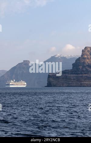 Santorini, Grecia - 7 settembre 2023: Veduta di una grande nave da crociera accanto al paesaggio vulcanico mozzafiato di Santorini Foto Stock