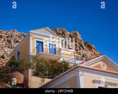 Graziosi dettagli di finestre, porte e balconi di una vecchia casa sull'isola di Simi. Vacanze nelle isole della Grecia da Rodi nel Mar Egeo. Case colorate in stile neoclassico nella baia di Symi. Informazioni generali sui viaggi di vacanza. Foto Stock