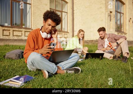 Gruppo di studenti adolescenti che studiano con computer portatili seduti a terra nel campus Foto Stock