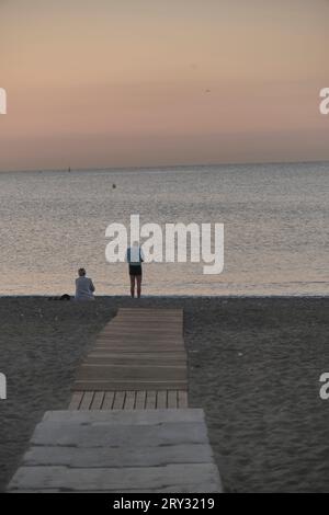 Coppia alla fine del passaggio pedonale sulla sabbia vicino all'alba del mare Foto Stock