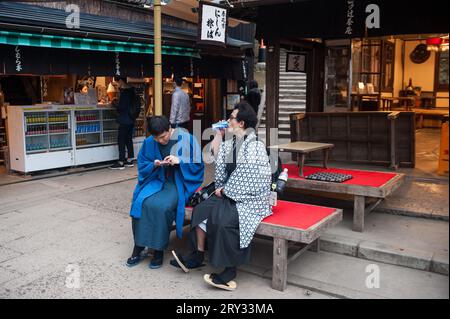 24.12.2017, Kyoto, Giappone, Asia - due giovani giapponesi che indossano abiti tradizionali riposano sul loro sentiero di pellegrinaggio al Monte Inari nel Fushimi Ward di Kyoto. Foto Stock