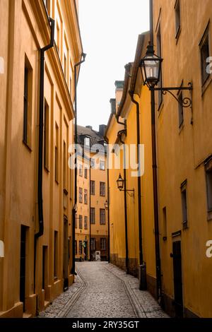 Case medievali in pietra gialla in uno storico vicolo urbano nel centro storico di Stoccolma, Gamla Stan, vicino alla via Bollhusgränd, nelle luminose giornate estive Foto Stock
