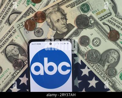 In questa immagine fotografica, il logo dell'American Broadcasting Company è visibile su uno smartphone con banconote e monete in dollari americani sul retro Foto Stock