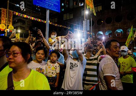 Hong Kong, Cina. 28 settembre 2023. La gente di Tai Hang guarda un drago che marcia attraverso una strada. Nel XIX secolo la gente del villaggio di Tai Hang a Hong Kong credeva di aver miracolosamente fermato una peste con una danza del drago del fuoco. Da allora, è diventata una tradizione annuale, dove fino a 300 artisti ballano la danza del drago di fuoco, composta da 72.000 bastoni di incenso bruciato e un drago lungo 67 metri, attraverso le strette strade di Tai Hang. Lo spettacolo attira una folla enorme anno dopo anno ed è tornato in piena forza dopo aver diminuito la partecipazione durante la pandemia di Covid-19. (IM credito Foto Stock