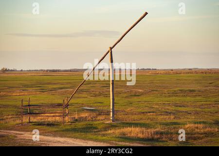 Un vecchio pozzo con una struttura in legno (shadoof) a Hortobágy, in Ungheria. Un punto di riferimento rurale. Tramonto. Foto Stock