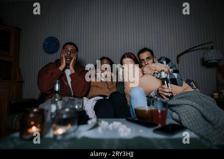Amici multirazziali spaventati che guardano un film spaventoso in cabina Foto Stock