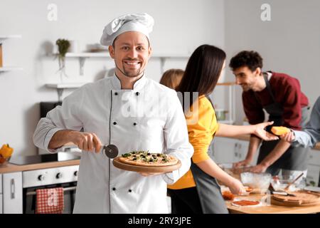 Chef italiano con pizza preparata durante la lezione di cucina in cucina Foto Stock