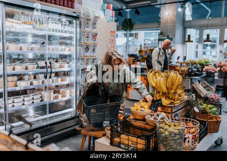 Donna anziana che compra banane al supermercato Foto Stock