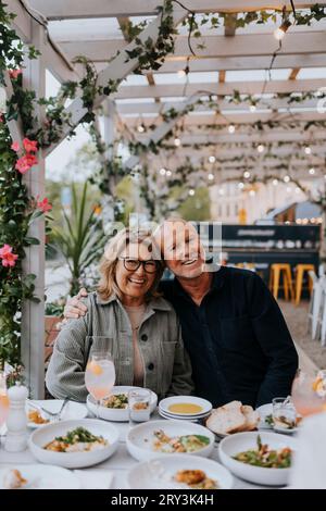 Amici anziani felici, maschi e femmine seduti a tavola al ristorante Foto Stock