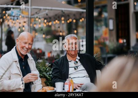Un uomo anziano felice che si diverte con gli amici al caffè del marciapiede Foto Stock