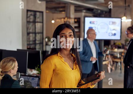 Ritratto di una donna d'affari sorridente che tiene in ufficio un tablet digitale Foto Stock