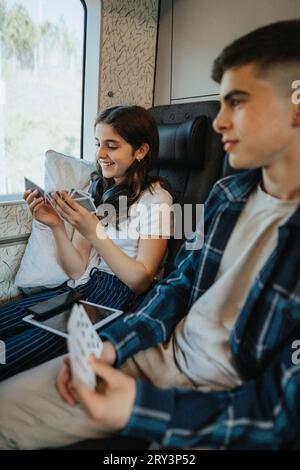 Ragazza sorridente che gioca a carte seduto accanto al fratello in treno Foto Stock