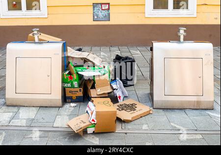 Maribor, Slovenia - 16 luglio 2023: Imballaggio di cartone di scarto davanti ai moderni contenitori di metallo Foto Stock