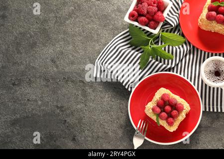 Pezzi di deliziosa torta Napoleone con lamponi freschi serviti su un tavolo grigio, piatto. Spazio per il testo Foto Stock