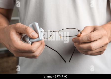 Uomo che pulisce gli occhiali con un panno in microfibra, primo piano Foto Stock