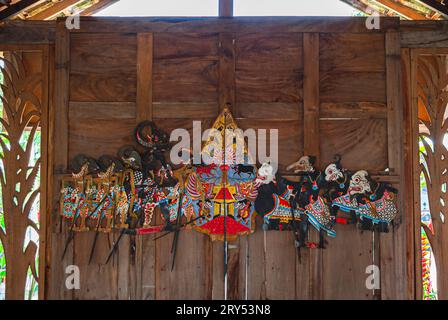 Wayang Kulit esposto su un muro di legno. Burattini d'ombra tradizionali indonesiani e giavesi in pelle. Foto Stock