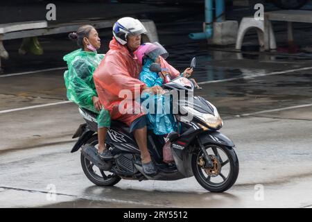 SAMUT PRAKAN, TAILANDIA, 20 settembre 2023, Una famiglia vestita di impermeabili sta cavalcando una moto sotto la pioggia Foto Stock