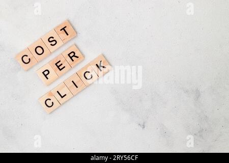 Vista dall'alto della parola costo per clic su blocco di lettere cubo in legno su sfondo bianco. Concetto aziendale Foto Stock