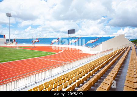 posti a sedere di tribuna gialla sullo stadio sportivo con un'arena all'aperto vuota Foto Stock