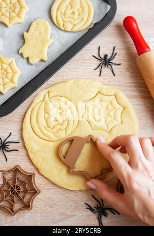 Preparazione di biscotti per le feste da cuocere in forno. Biscotti di Halloween pronti da cuocere a forma di zucche e fantasmi Foto Stock