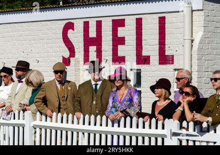 Visitatori in costumi d'epoca al circuito motoristico Goodwood Revival. Persone in abbigliamento vintage. Femmine in costume. Retro Shell. Signori Foto Stock