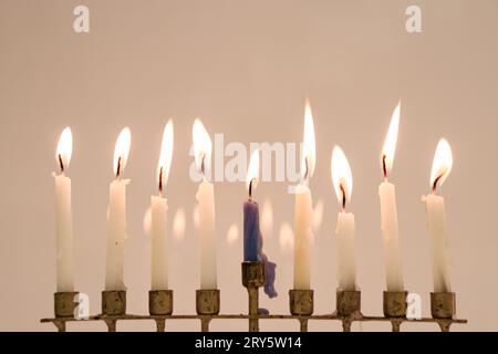 Una menorah completa nell'ultima notte di Hanukkah. Otto candele bianche e il centro è blu. Tutte le candele sono accese e riflettono sul retro Foto Stock