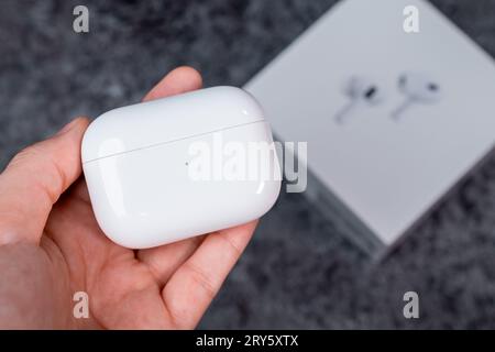 Jurmala, Lettonia - 21 09 2023: Nella mano di una donna c'è una custodia con cuffie - AirPods Pro 2 Generation. Scatola delle cuffie Apple sullo sfondo. Foto Stock