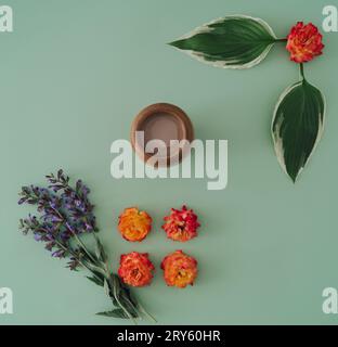 Elegante allestimento estivo minimale composto da fiori, foglie verdi e una tazza di caffè. Idea di composizione della natura. Concetto di tavoletta del caffè. Estetica floreale Foto Stock