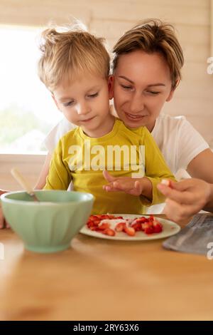 Un figlio e una madre bionda caucasici che fanno colazione con cibo delizioso Foto Stock