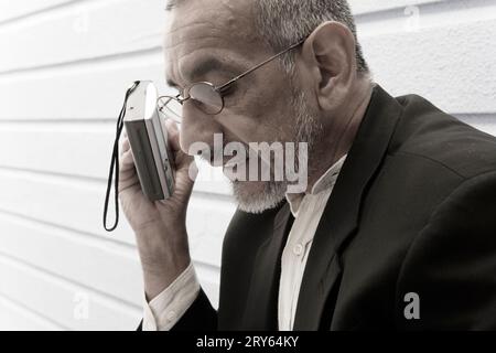 Un uomo con un dispositivo elettronico in mano. Foto Stock