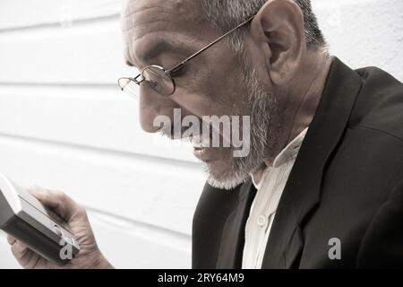 Un uomo con un dispositivo elettronico in mano. Foto Stock