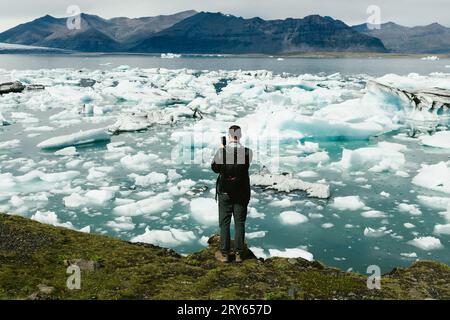 L'uomo scatta foto della laguna glaciale e delle montagne sul cellulare Foto Stock