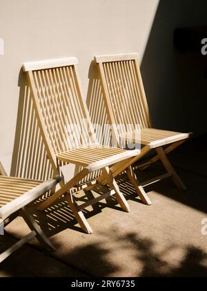 Sedie a sdraio in legno all'aperto illuminate dal sole con ombre Foto Stock