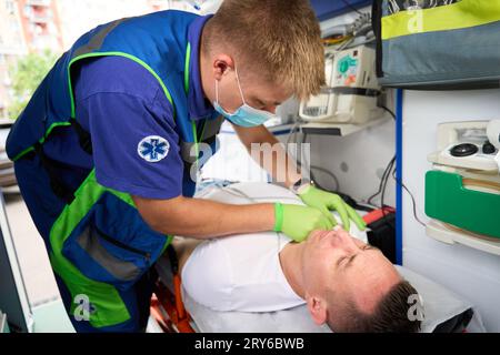 Il paramedico maschile mette un gocciolamento su un paziente in ambulanza Foto Stock