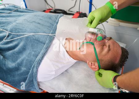 Paramedic mette la maschera di ossigeno sul paziente in ambulanza Foto Stock