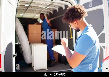 I traslocatori che controllano le caselle di consegna e compilano il documento Foto Stock