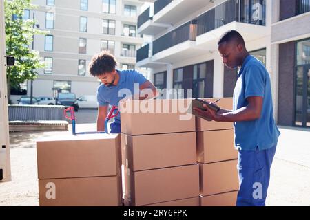 I traslocatori che controllano le caselle di consegna e compilano il documento Foto Stock