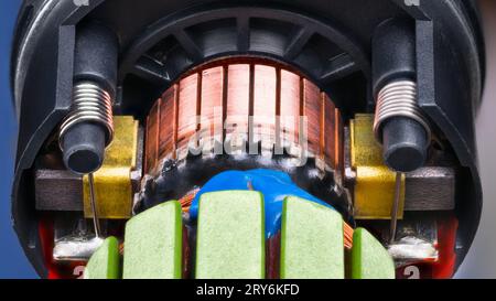 Primo piano del rotore del motore elettrico CC con filo di rame fissato tramite epossidico blu in un contenitore in plastica nera. Collettore con contatti spazzola di carbone all'interno del motore. Foto Stock